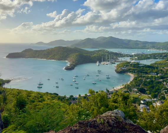 Scenic view of English Harbour in Antigua, with sailboats and yachts anchored in turquoise bays surrounded by green hills.